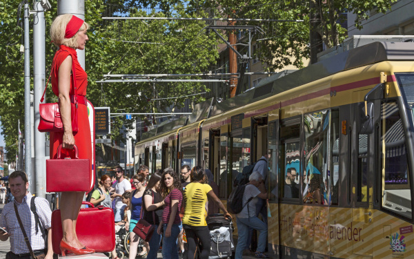 A woman in red is standing on a power box in the middle of the pedestrian zone