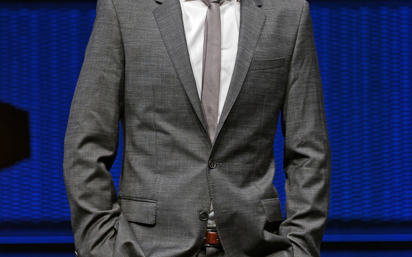 A man in a suit, standing on a stage.