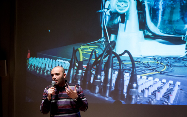 A man standing in front of a canvas and talking to the audience