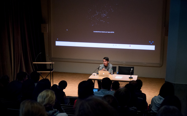 A man sitting at the table and addresses the audience.