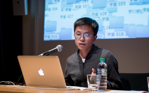 A man sitting at the table and addresses the audience.