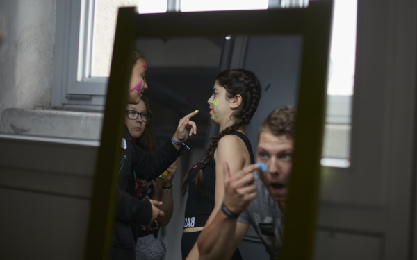 Teenagers putting on make-up in neon colors.