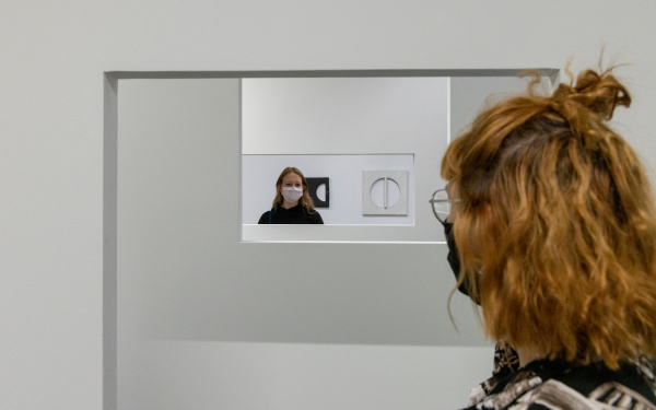 Zwei Frauen in Nahaufnahme. Sie stehen sich gegenüber und schauen sich durch eine Hängekonstruktion hindurch an.