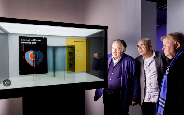 Peter Weibel vor einer Vitrine mit virtuellen Büchern in der Ausstellung »Writing the History of the Future«