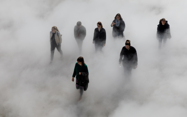 The photo shows seven laughing people walking across the Human Rights Square, partly covered by fog.