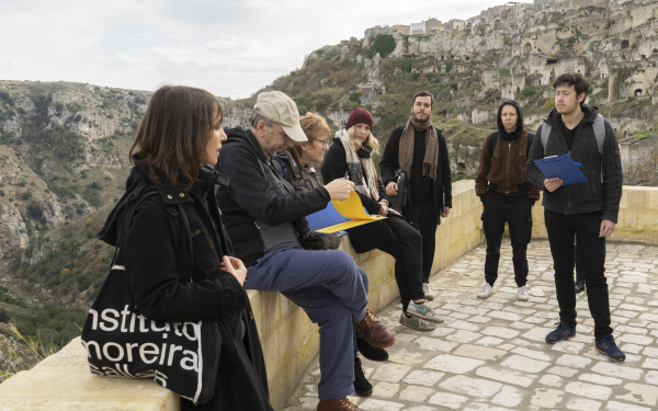 Eine Gruppe von Menschen stehen im freien vor einer bergigen Landschaft.