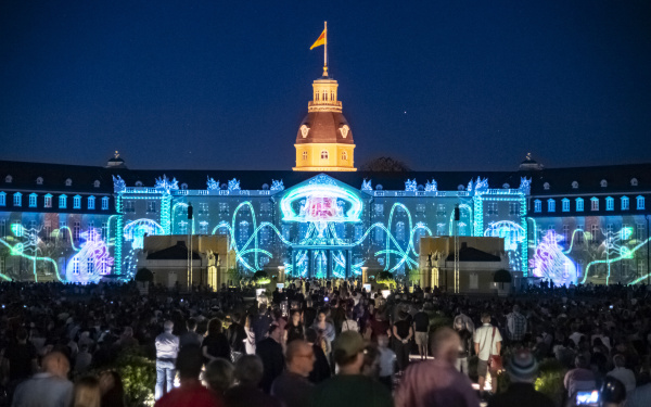 Eine riesige digitale Qualle streckt ihre Tentakeln über die Seitenflügel des Karlsruher Schlosses aus. 