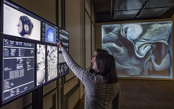 Zwei Frauen stehen vor einem Bildschirm in der Ausstellung »Open Codes. Die Welt als Datenfeld«