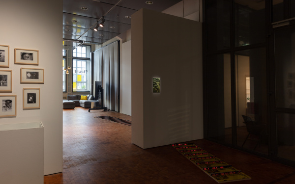 Blick in die Ausstellung auf das Werk »Patterns of Heat« mit am Boden platzierten verspiegelten Platten, rot leuchtenden Streben und einer beleuchteten, an der Wand hängenden Abbildung einer Landschaft