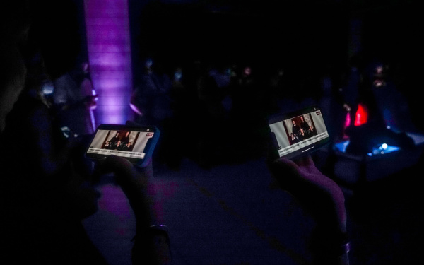 You can see two hands, each holding up a smartphone.