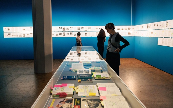 Zu sehen ist eine Person, die einen Ausstellungstisch mit Büchern betrachtet.