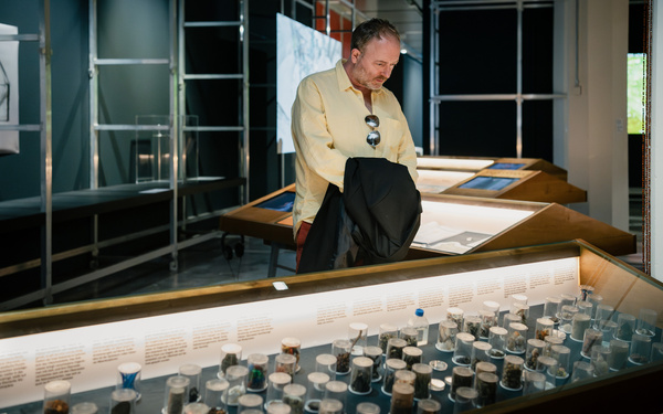 Zu sehen ist eine Person, die sich Exponate in einer Vitrine ansieht.