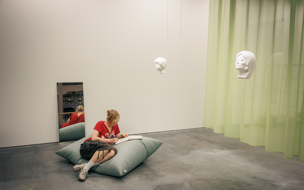 The picture shows a person sitting on a cushion and writing something in a notebook.