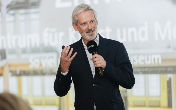 The photo shows Alistair Hudson giving a speech.