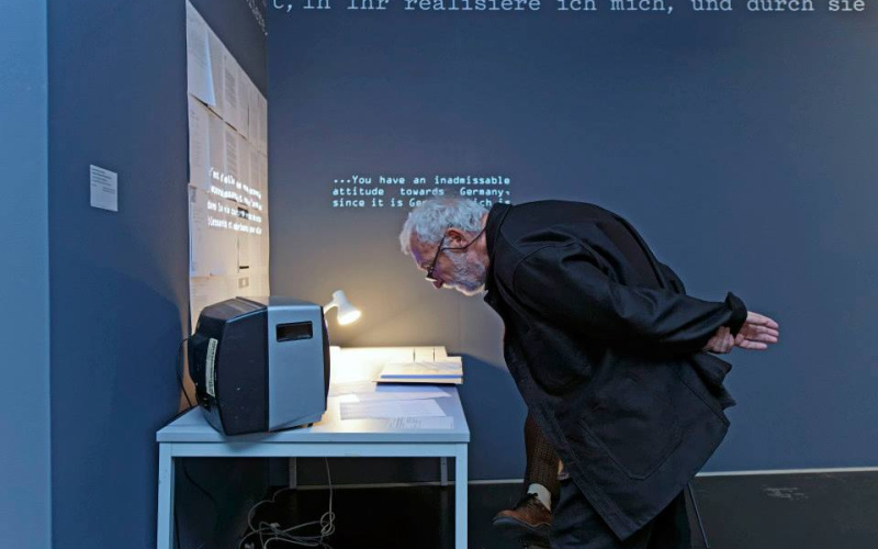 Ein Mann liest vor einem kleinen Bildschirm die Beschreibung