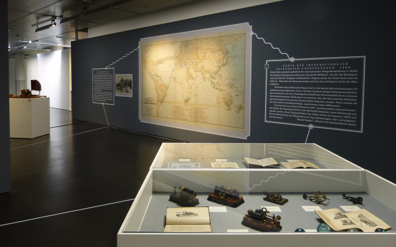 Schaukästen mit alten Telegrafen und eine große Landkarte an der Wand