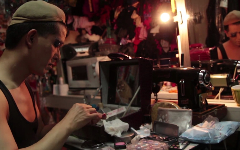A Man putting on his make-up in front of a mirror
