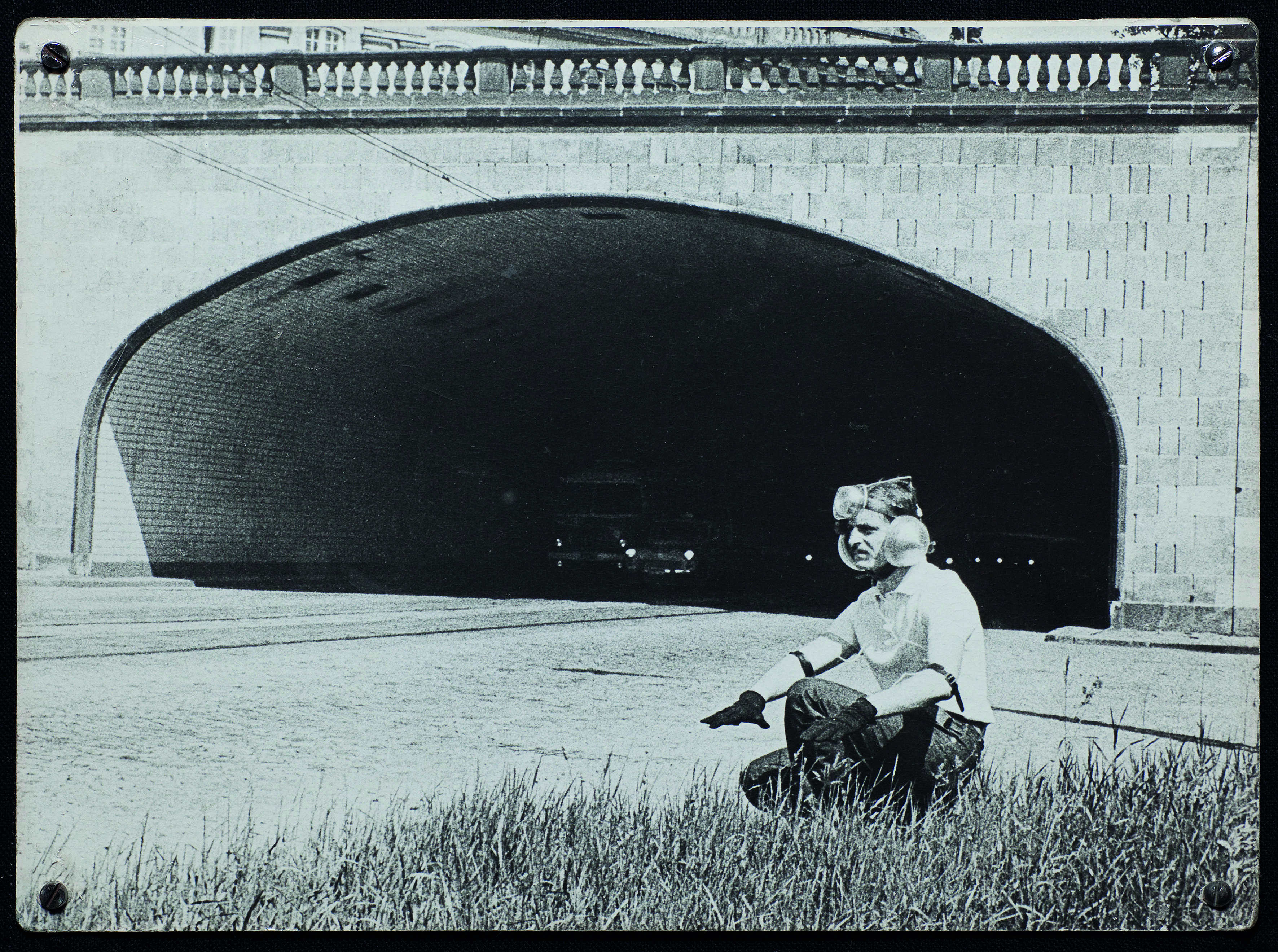 The black and white photo shows a man with a technical installation on his head, his ears covered with sound barriers.