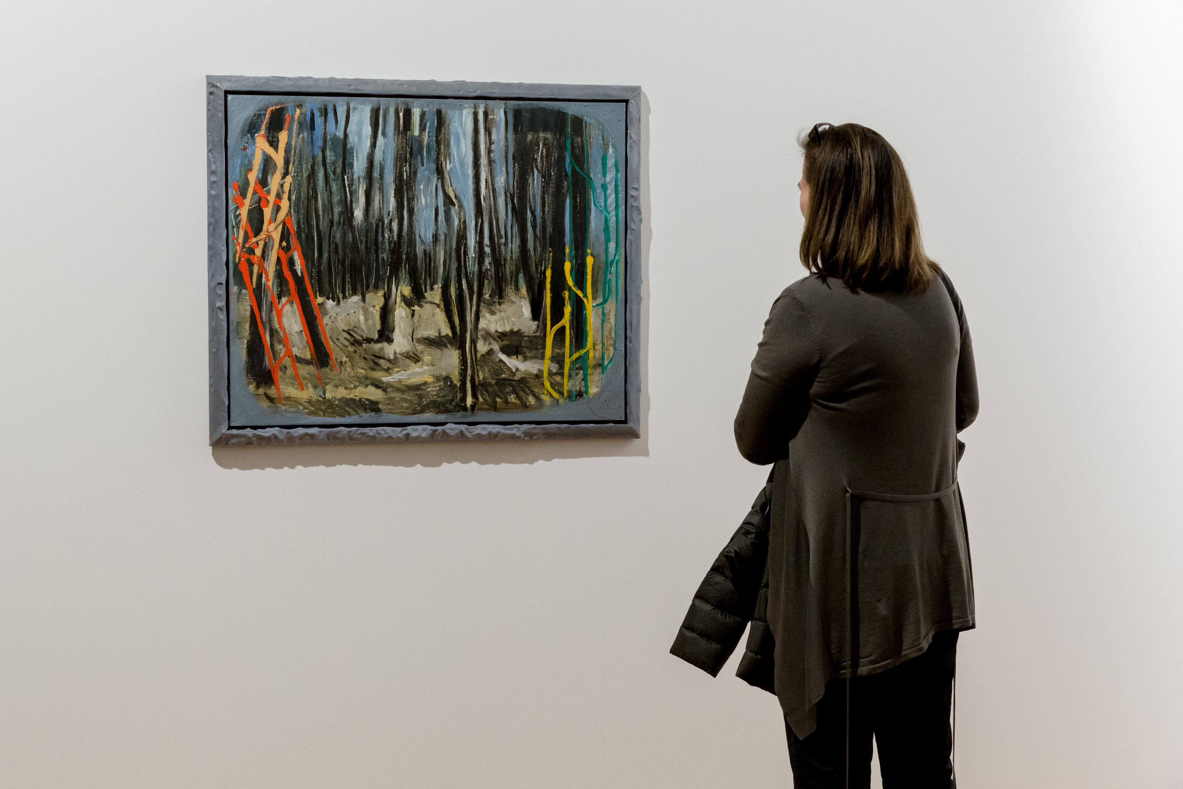 The picture shows a woman in front of a painting by Markus Lüperz