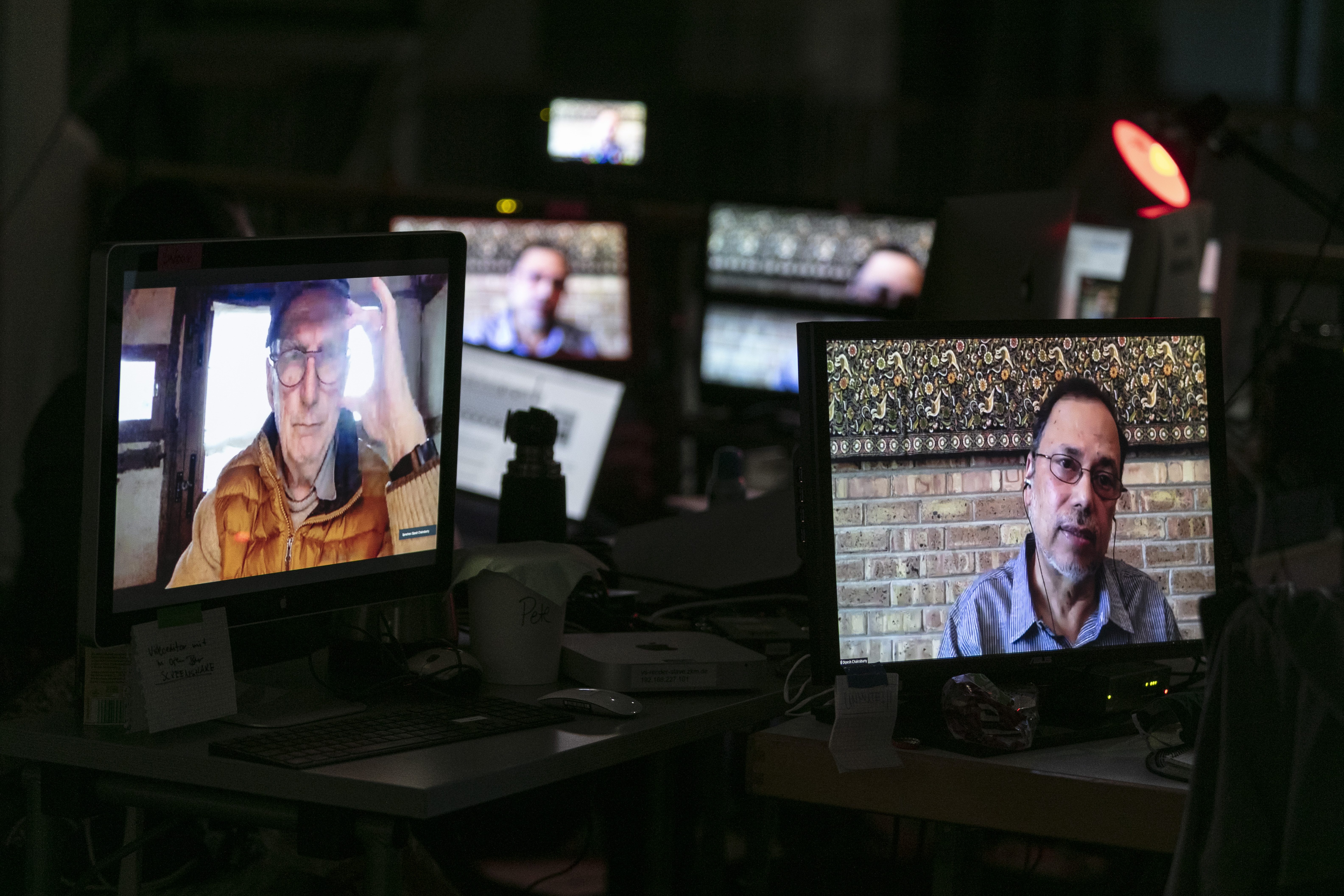 Mehrere kleine Bildschirme zeigen die Gesichter von Bruno Latour und Dipesh Chakrabarty.