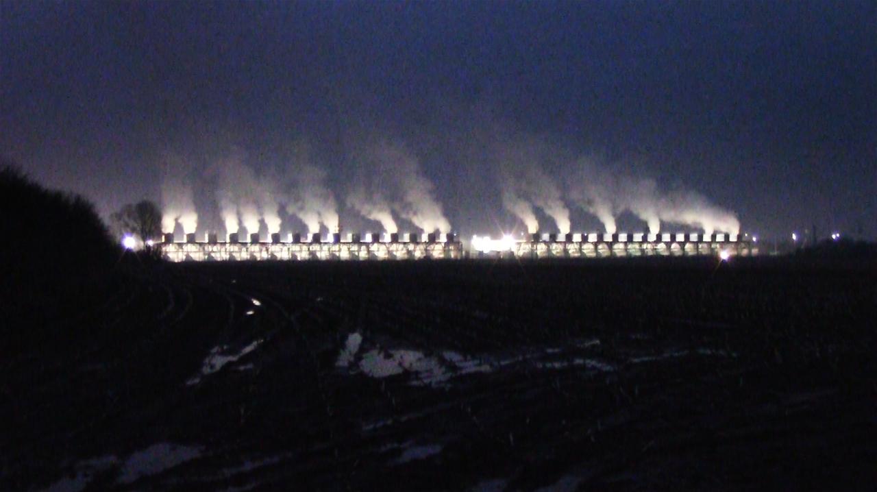 Nächtliche Fotografie in dunklen blauen Tönen mit Licht und Rauch am Horizont