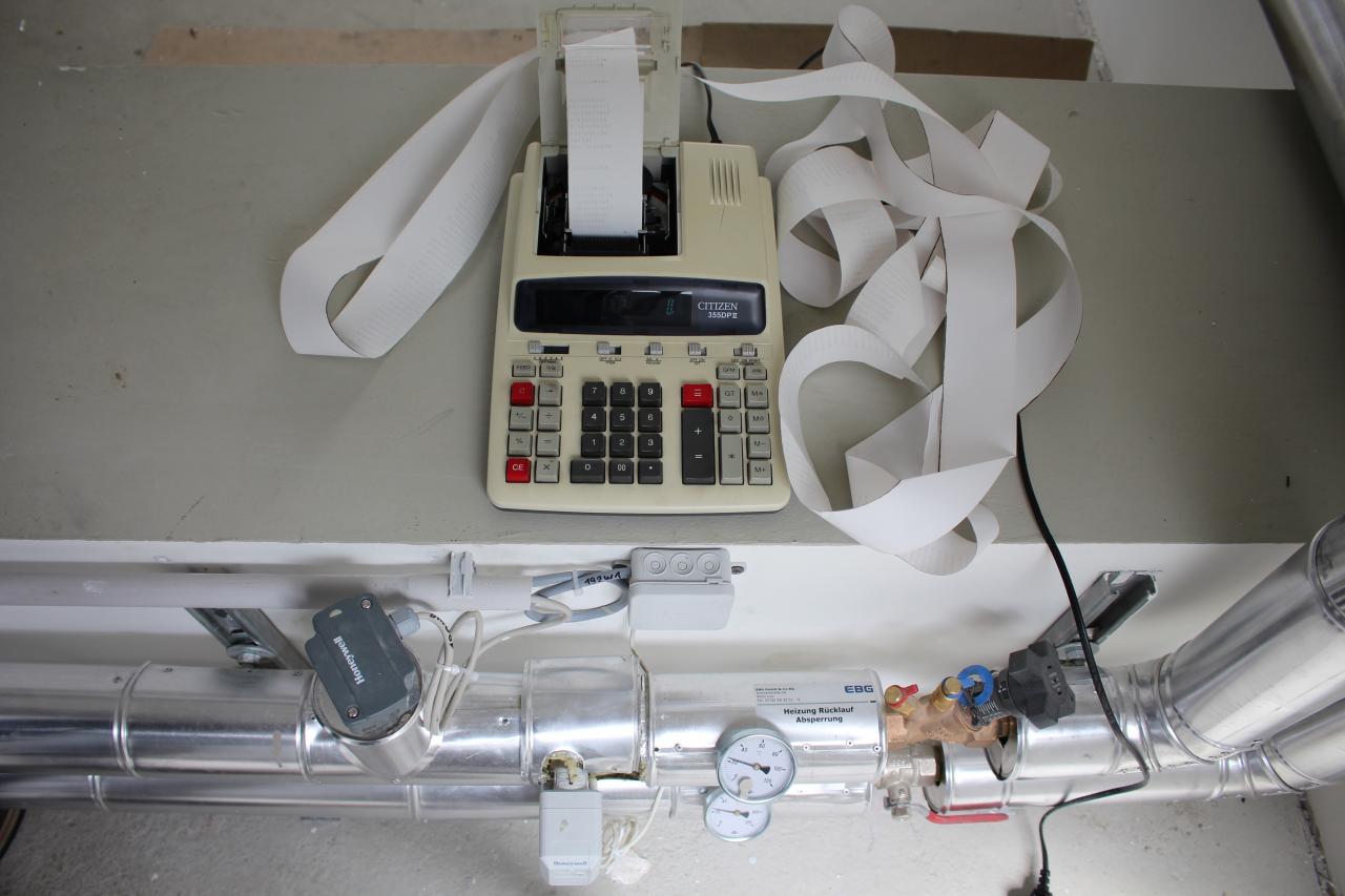 A cash register with a long, printed receipt in front of a system of tubes and displays