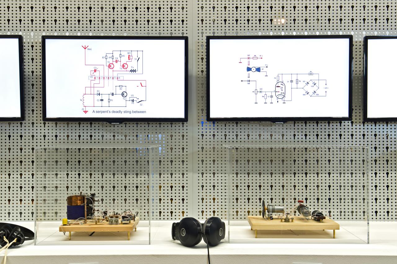 Installation mit Bildschirmen, Kopfhörern und kleinen Apparaturen