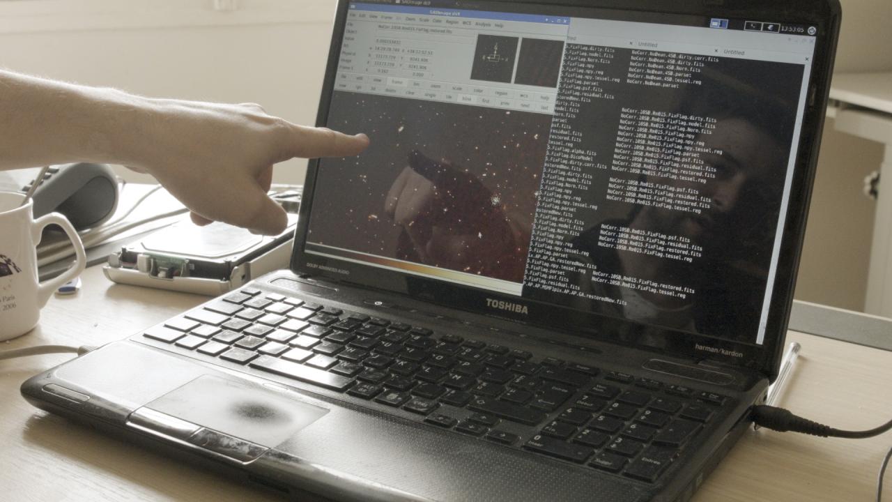 A male hand points to a computer screen