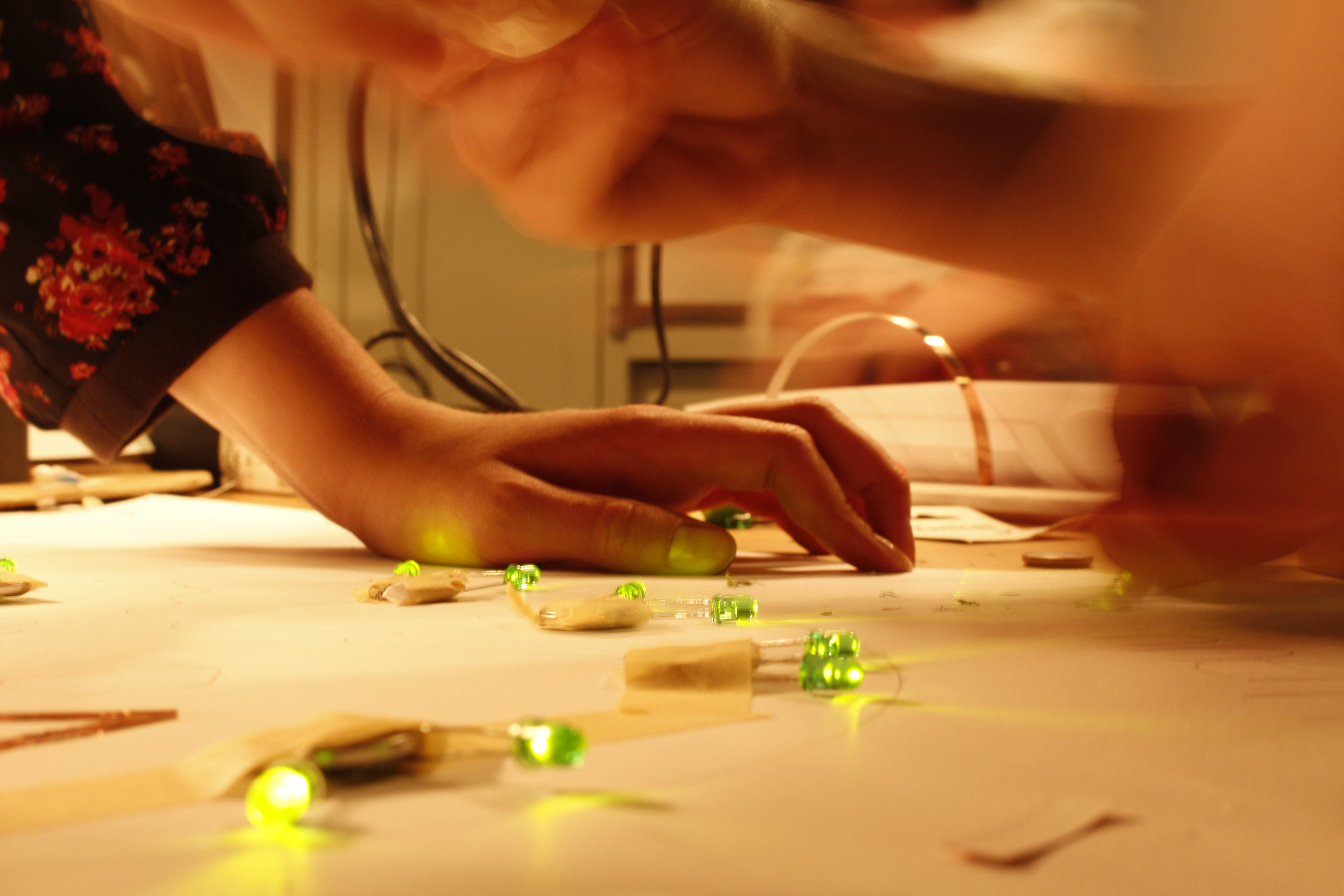 One can see a hand, that is leaning on a table on which - taped to a sheet of paper - green LEDs are glowing.