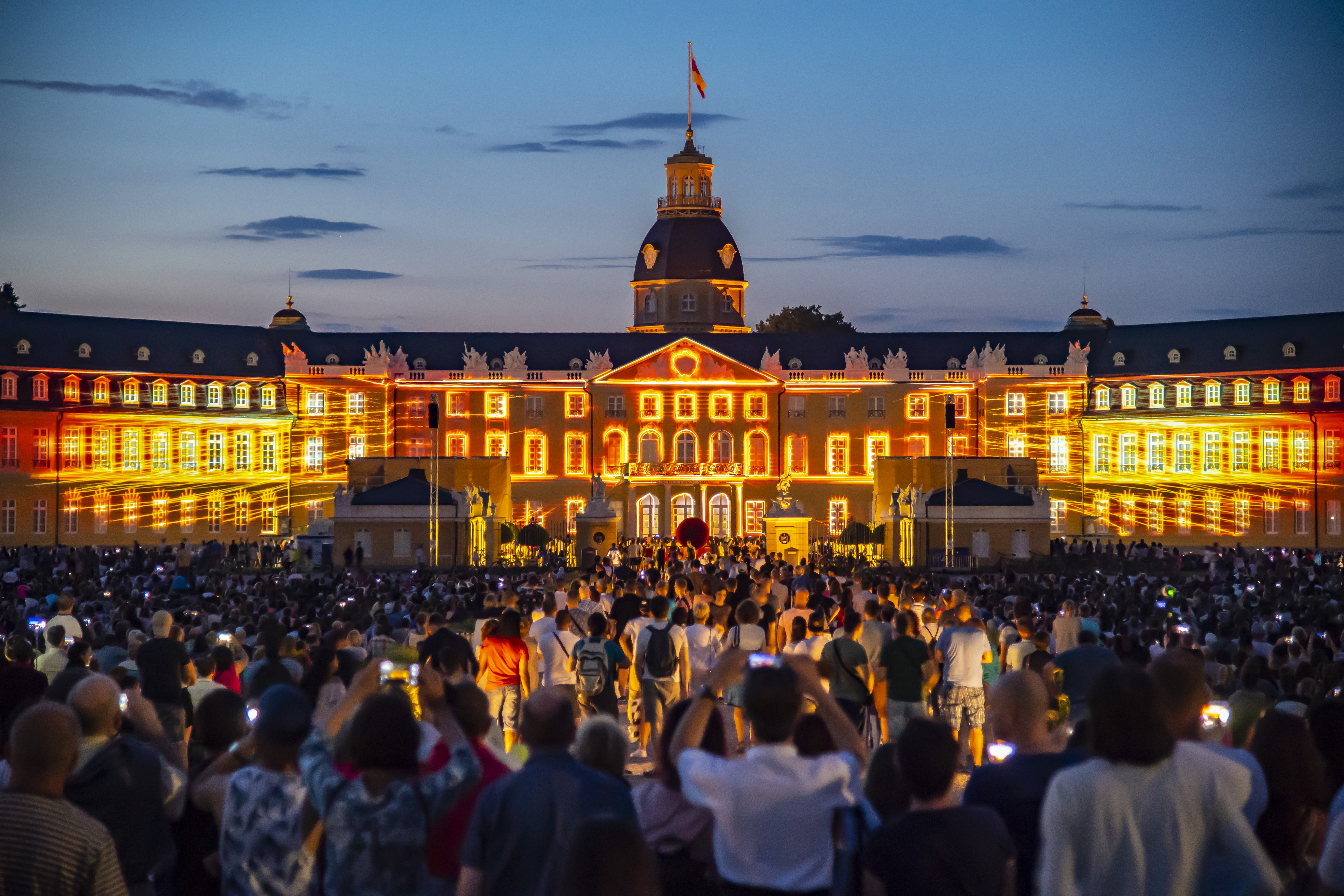 Die Fassade des Karlsruher Schlosses ist bei Nacht erleuchtet.