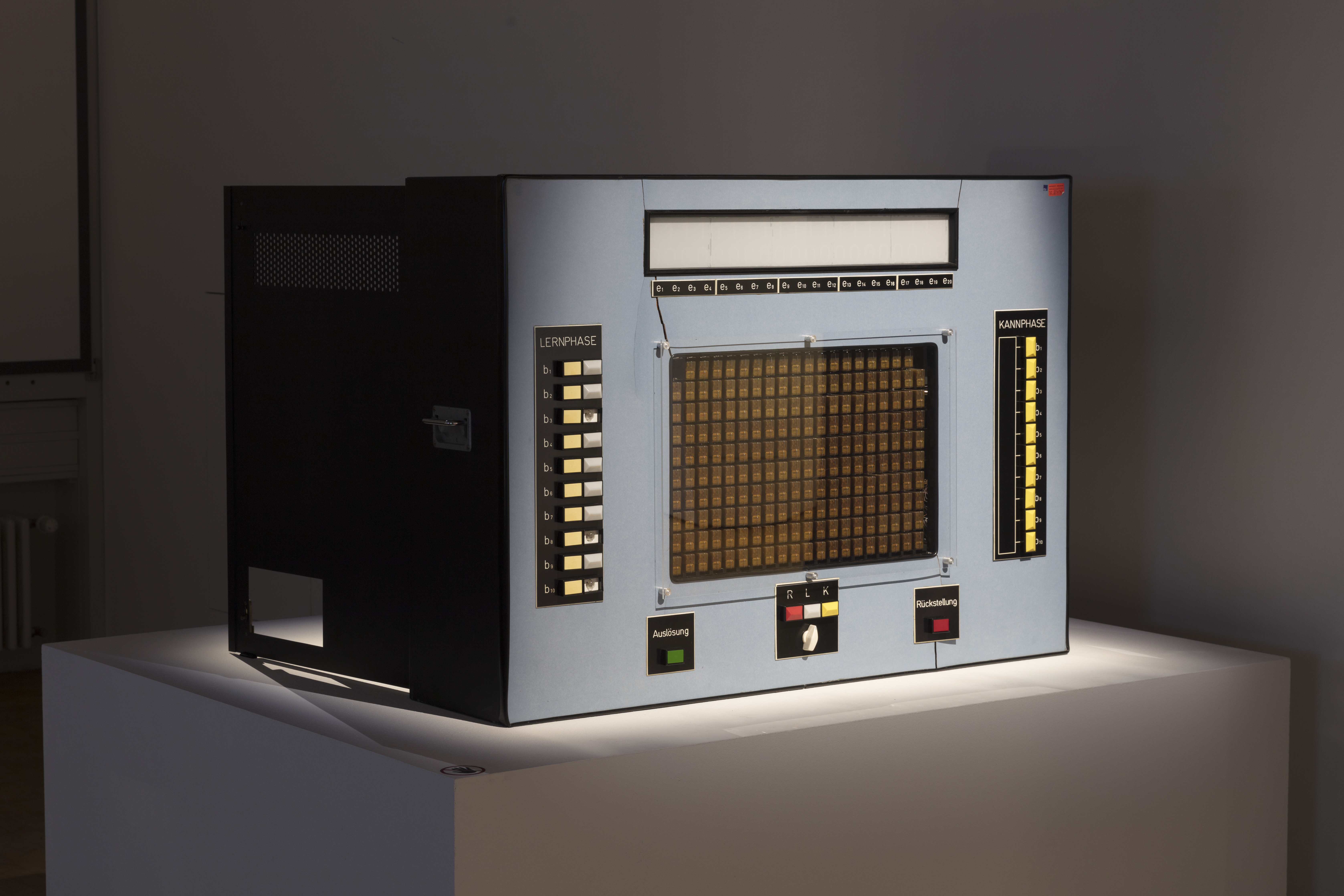 A learning computer from the 60s, rectangular, in grey and with many buttons.