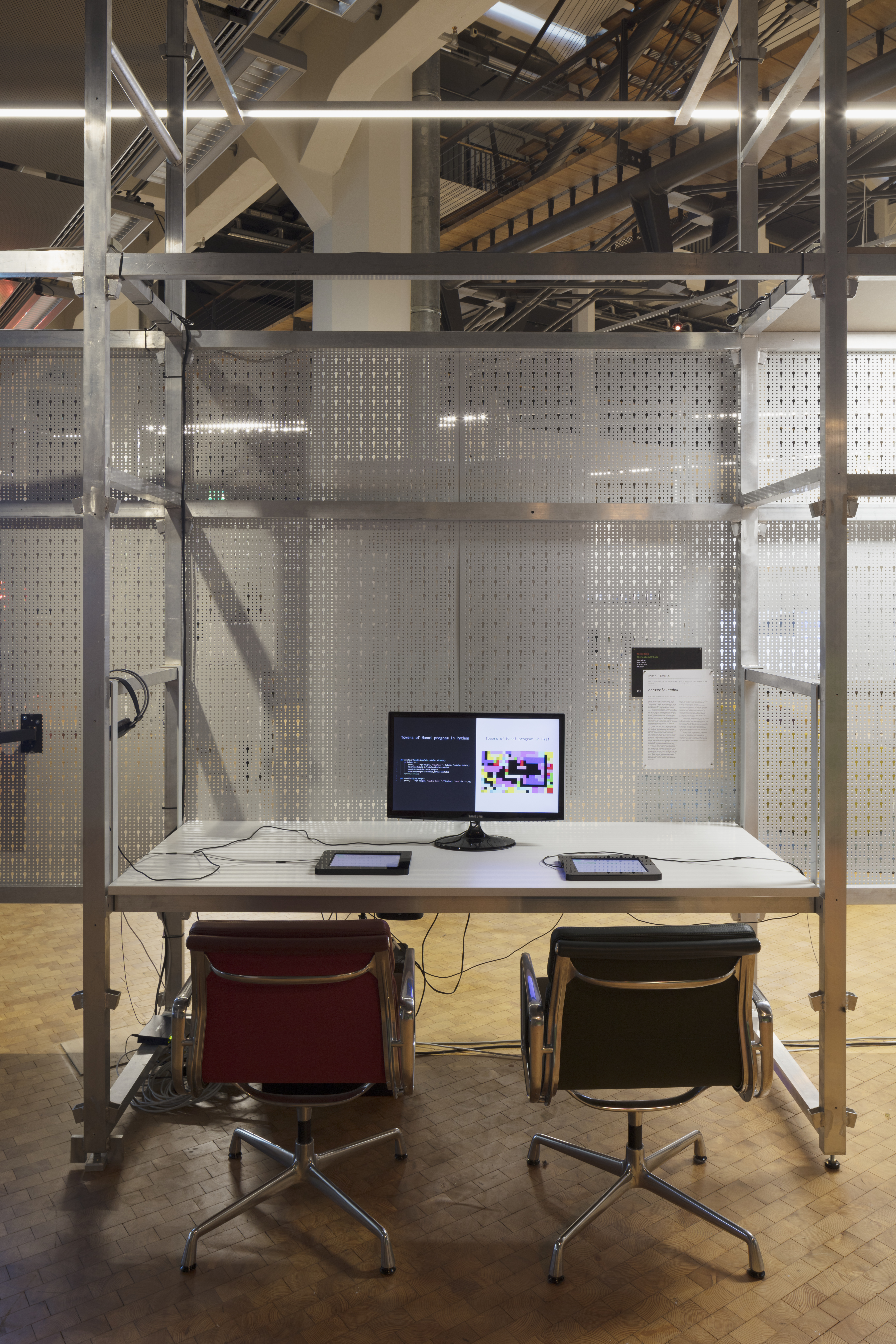 A desk with monitor and two chairs