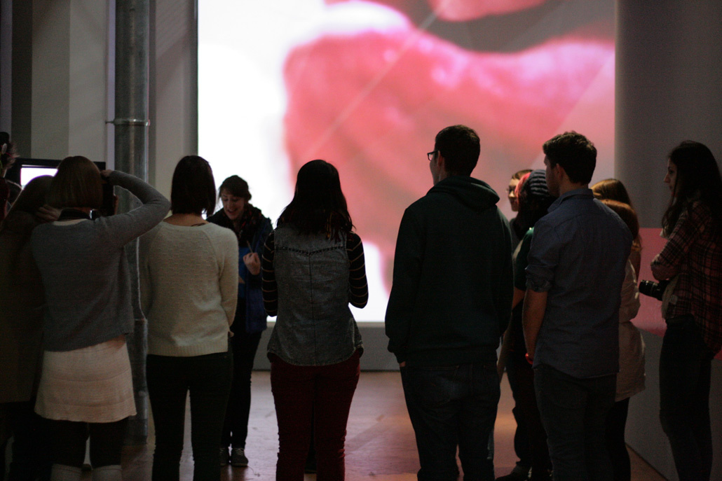 A group of people in front of an art educator. In the background can be seen a large area part of a tongue.