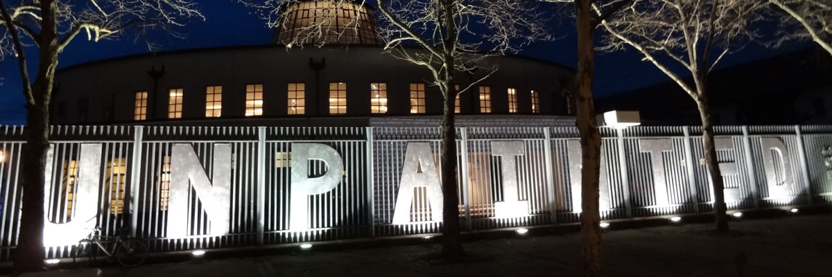 Night scene: On a fence, the letters "UNPAINTED" are attached.