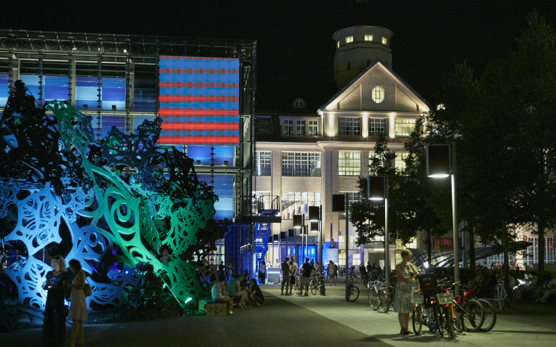 Hallengebäude mit einer  beleuchteten Skulptur bei Nacht