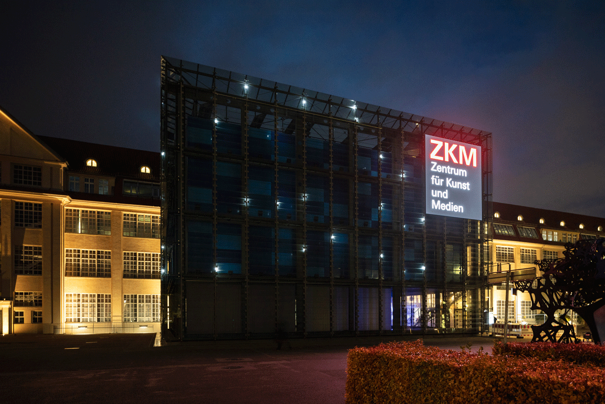 Der gläserne Kubus des ZKM funkelt im Dunkeln mit hellen Lichtpunkten. Eine Installation von Walter Giers.