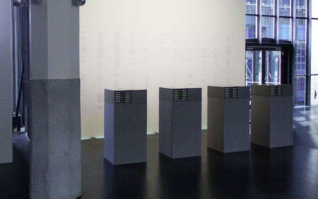 Four gray filing cabinets in front of a brightly lit wall.