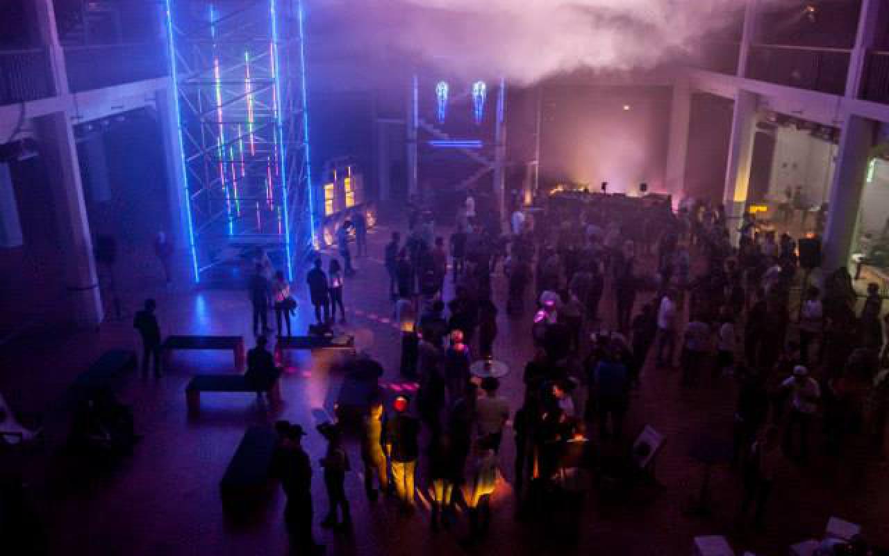 Menschen tanzen unter einer Wolke in einem geschlossenen Raum