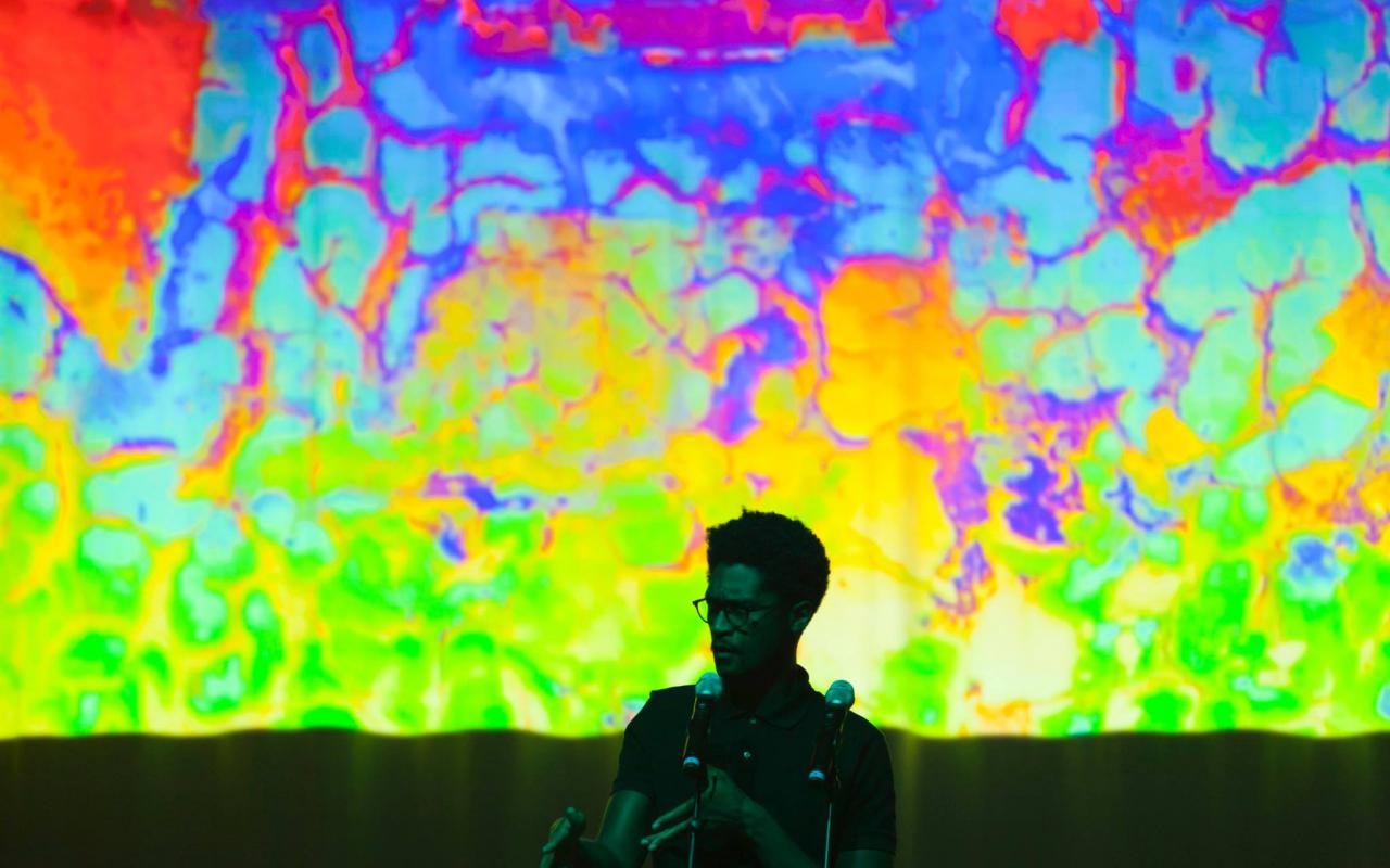 A man stands in front of a colorful screen