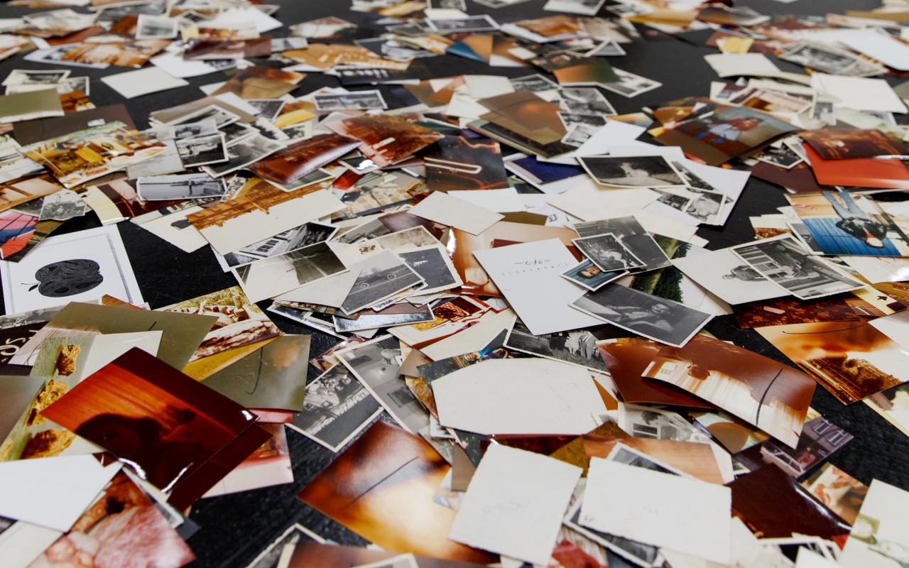 Eine Installation von Dieter Hacker. Auf dem Boden des Ausstellungsraums sind farbige Fotografien verteilt.
