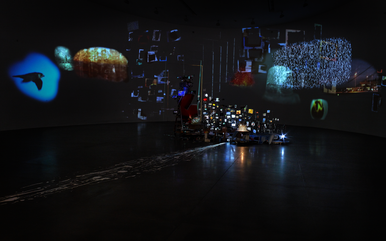 Photo of a dark exhibition room with luminous reflections.