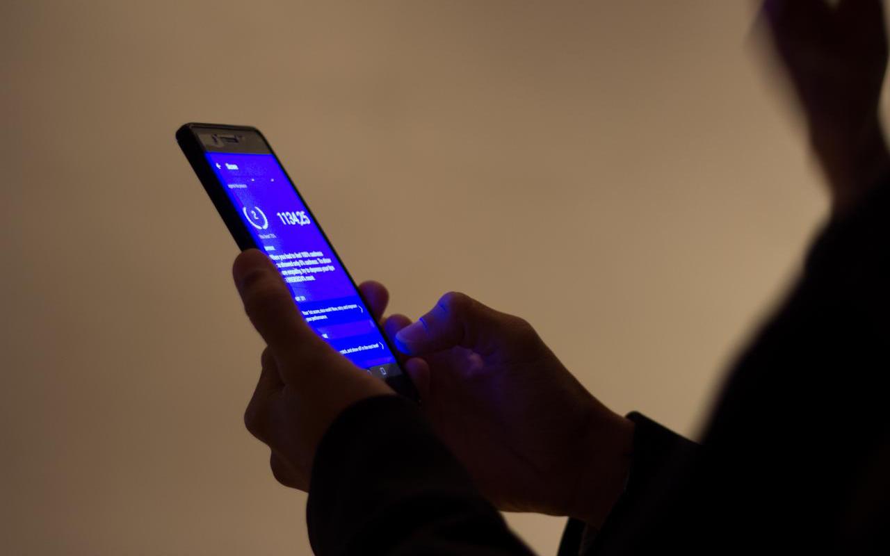 Hands operate a mobile phone with a blue screen