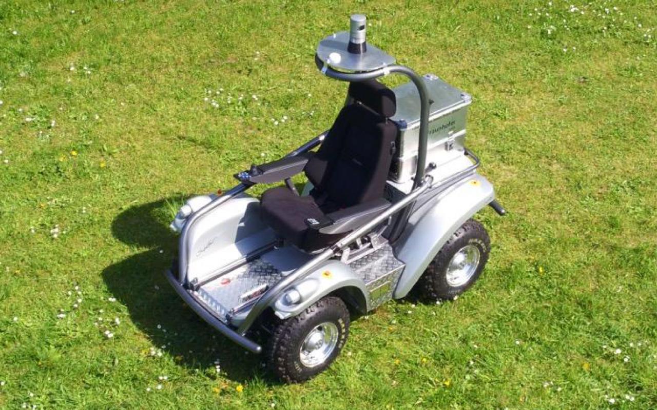 Grey vehicle with black seat on a green meadow
