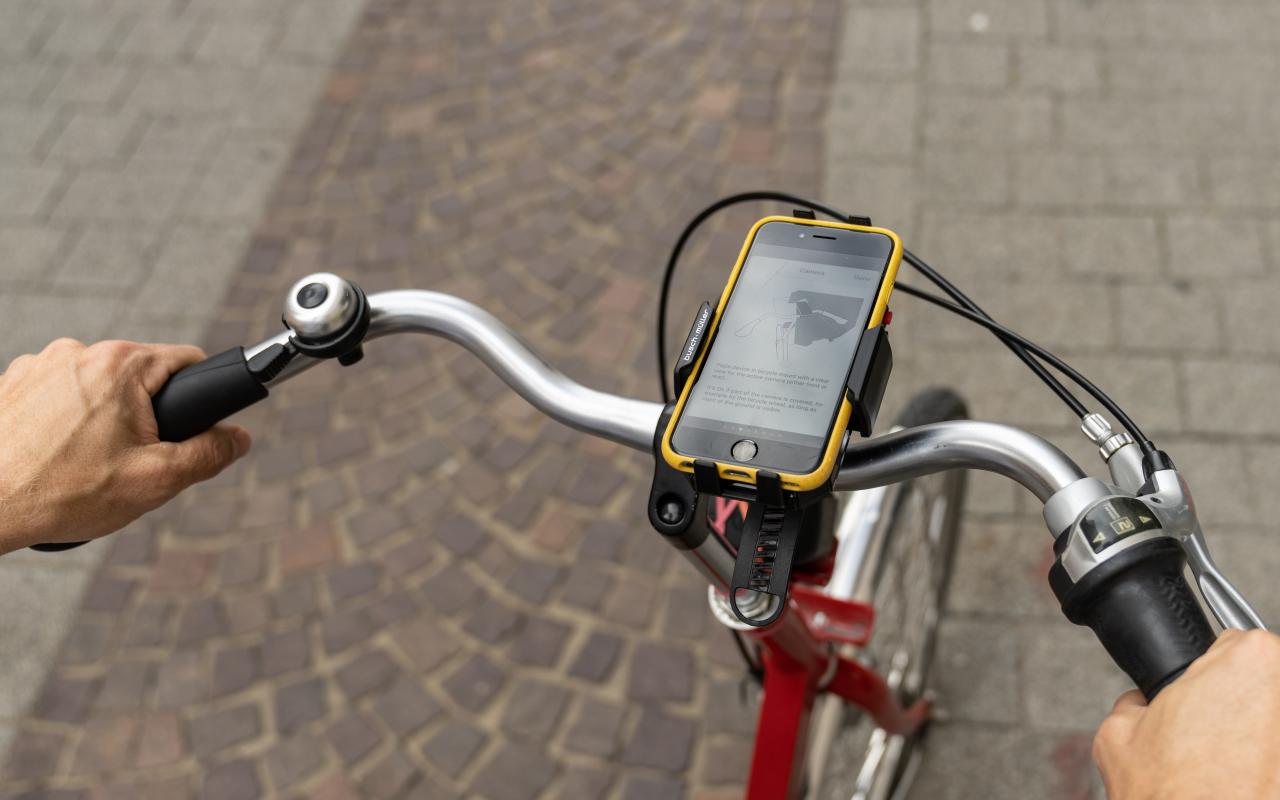 Zu sehen ist ein Ausschnitt von einem Fahrrad mit einem Handy auf der Handy-Halterung am Lenkrad.