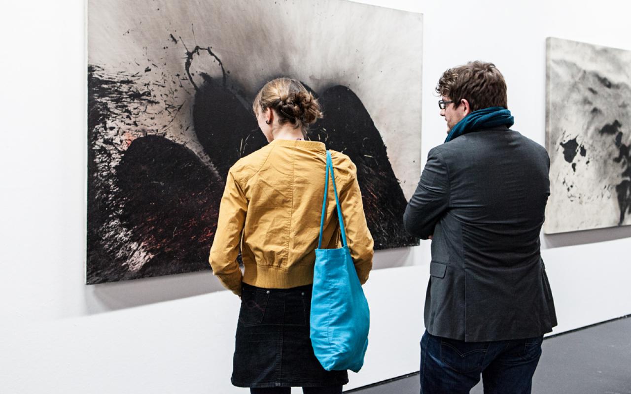 Two people standing in front of Otto Piene's images.