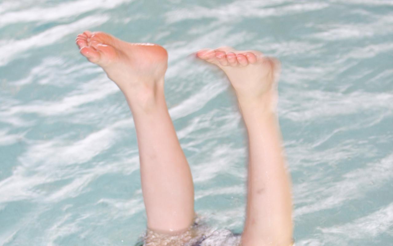 The photo shows two children's feet looking out of the water. 