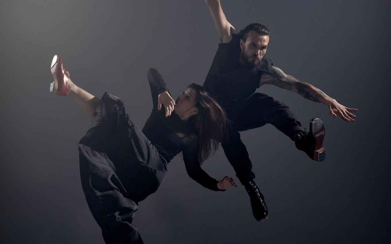 You can see two dancers:inside in black clothes in front of dark gray background