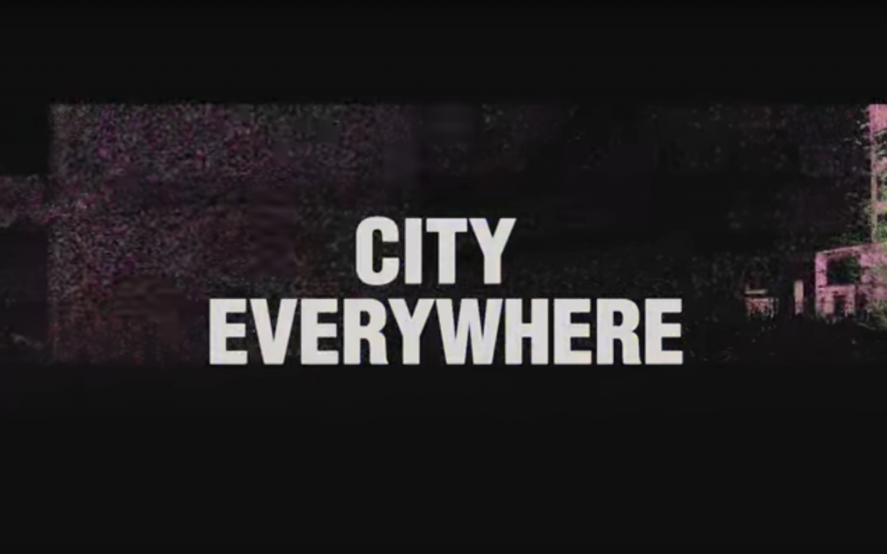 Der Schriftzug »City Everywhere« vor einem schwarzen Hintergrund mit Industrie-Gebäude.
