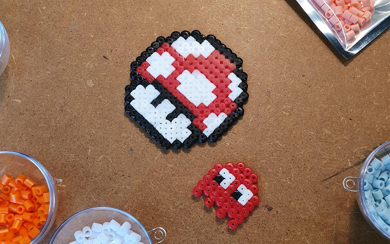 Photo of a red toadstool from Super Mario and a ghost from Pacman – both made from iron-on beads.