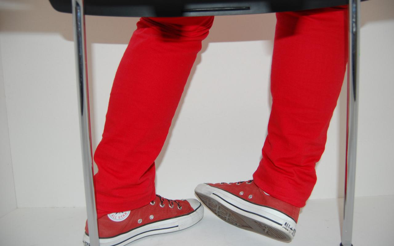 Schnappschuss bei einer Fotosafari: metallene Stuhlbeine und Kinderbeine und Füße, die in roten Turnschuhen und einer roten Hose stecken.
